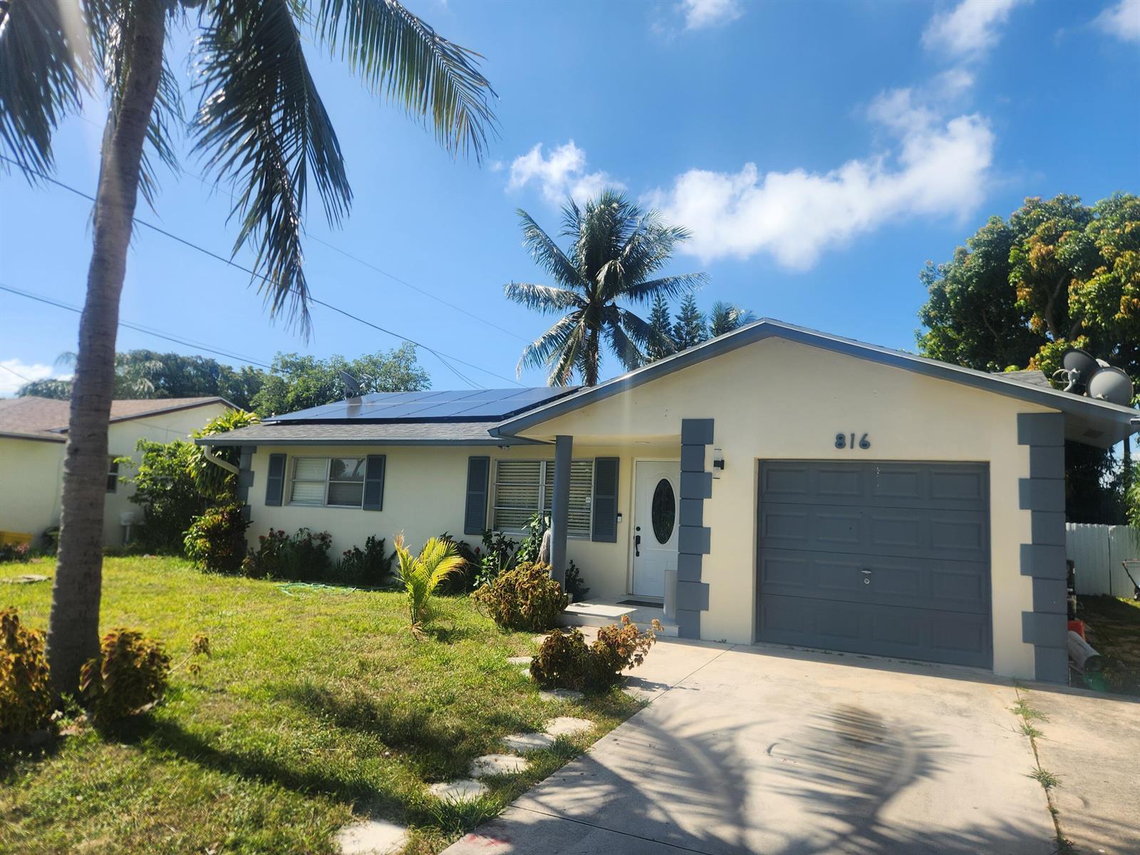 A single-story house with a gray garage, solar panels on the roof, and palm trees — 816 NW 8th Avenue, Boynton Beach FL 33426, BOYNTON BEACH, FL