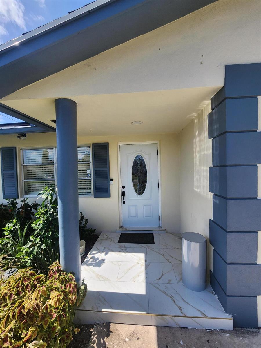 A front entryway features a white door with an oval window, tiled porch, and columns — 816 NW 8th Avenue, Boynton Beach FL 33426, BOYNTON BEACH, FL