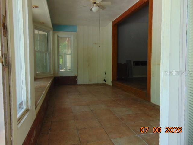 An interior view of a sunroom featuring tiled flooring, a ceiling fan, and large windows — 2105 NW 16TH TERRACE NW, GAINESVILLE, FL
