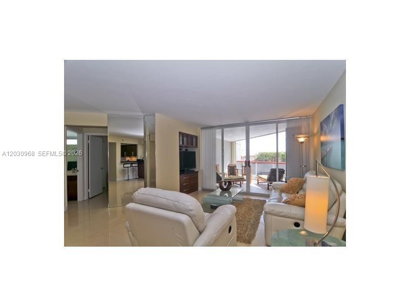 A living room features white leather furniture, a glass coffee table, and a balcony view — 6767 Collins Ave # 206, Miami Beach FL 33141, MIAMI BEACH, FL