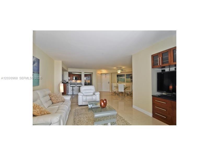 A living room features a white leather sofa, a recliner, and a wooden media console — 6767 Collins Ave # 206, Miami Beach FL 33141, MIAMI BEACH, FL