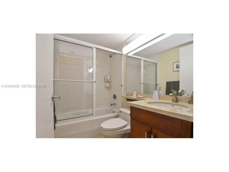 A bathroom features a vanity with a stone countertop, a toilet, and a shower-tub combination — 6767 Collins Ave # 206, Miami Beach FL 33141, MIAMI BEACH, FL