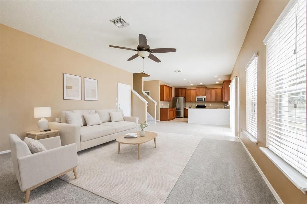 A living room with beige walls, a white sofa, and an open kitchen in the background — 30207 CHEVAL STREET, MOUNT DORA, FL