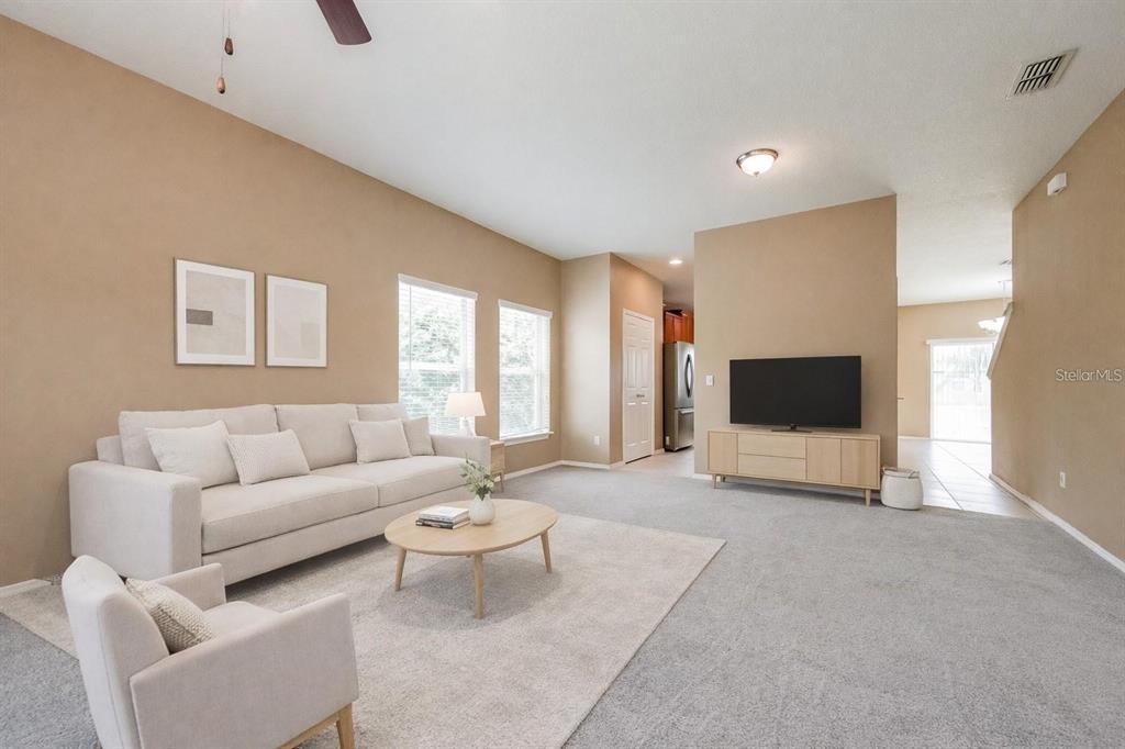 A living room features a beige sofa, a round coffee table, and a television console — 30207 CHEVAL STREET, MOUNT DORA, FL