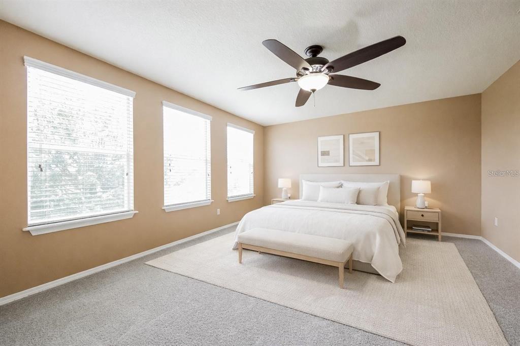 A bedroom features a bed with a bench, two nightstands, and three windows — 30207 CHEVAL STREET, MOUNT DORA, FL