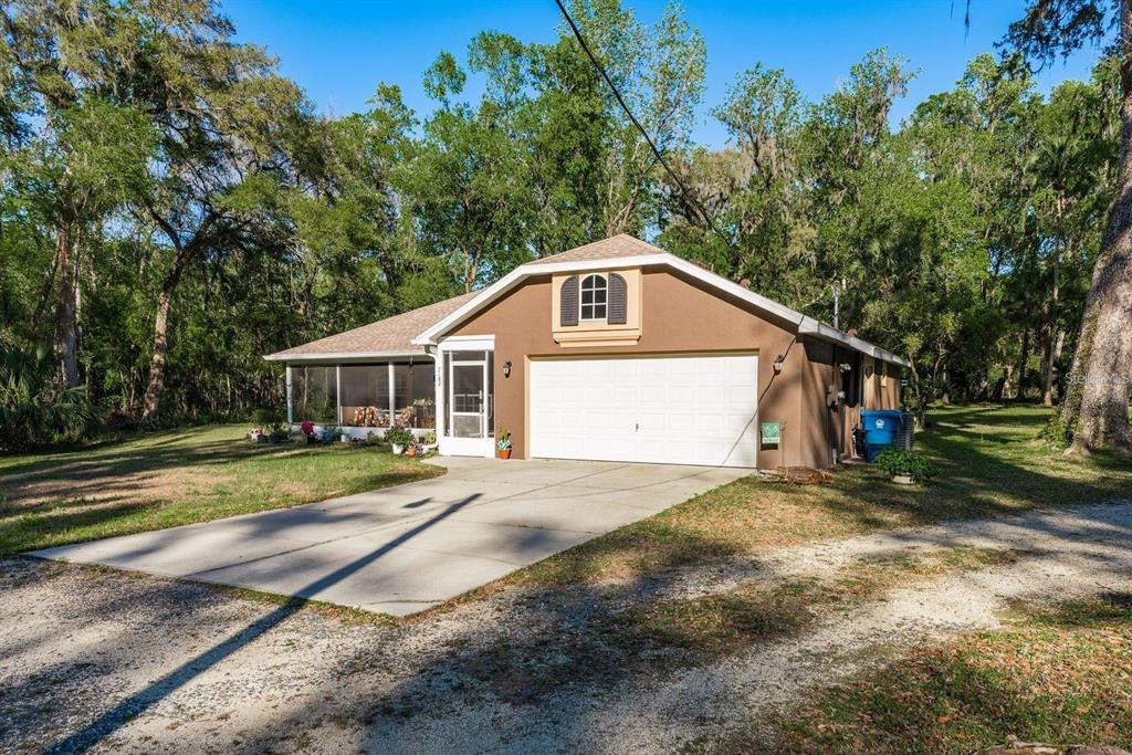 A brown single-story house with a white garage door and a screened-in porch — 7182 GRIFFIN ROAD, BROOKSVILLE, FL
