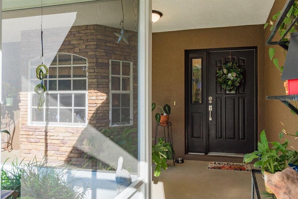 A covered entryway features a dark front door with a wreath and stone siding — 7182 GRIFFIN ROAD, BROOKSVILLE, FL