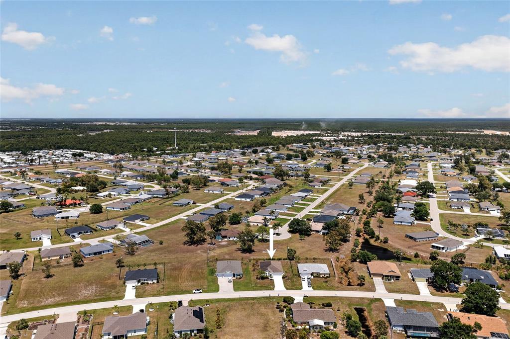 An aerial view shows a suburban neighborhood with a white arrow pointing to a house — 25174 ALCAZAR DRIVE, PUNTA GORDA, FL