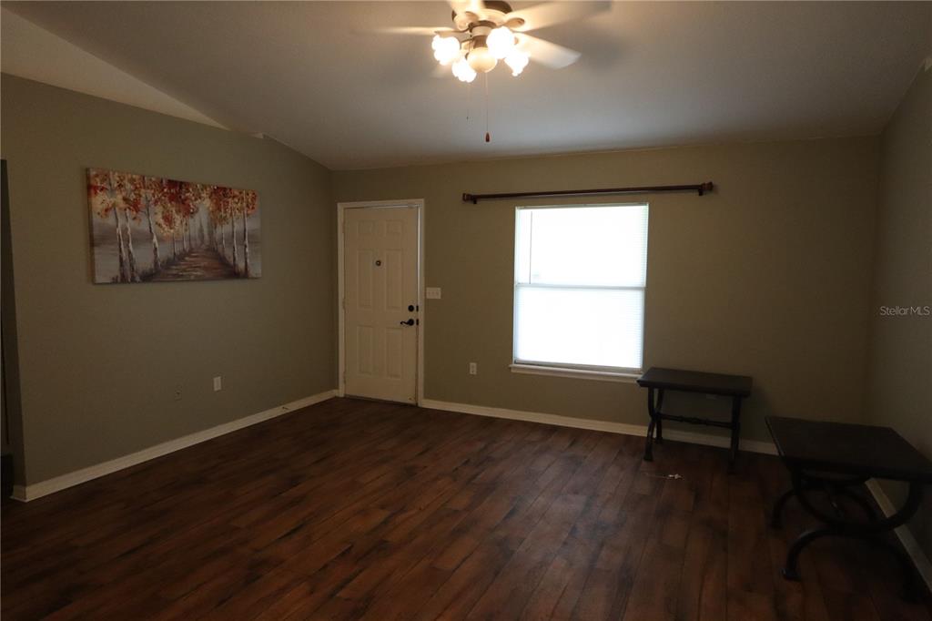 A living room features wood-look flooring, a ceiling fan, a window, and a front door — 8 HEMLOCK TERRACE, OCALA, FL