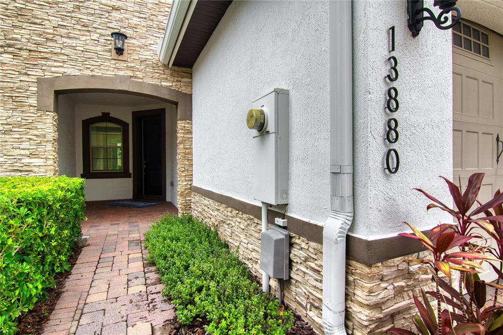 The exterior of a house features a stone-accented wall, a paved walkway, and house numbers — 13880 ARCLID STREET, ORLANDO, FL