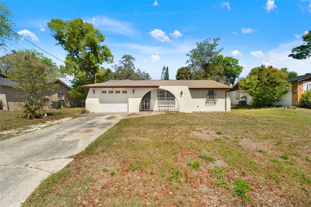A single-story house with a white stucco exterior, arched entryway, and a concrete driveway — 8511 LONG BOAT LANE, HUDSON, FL