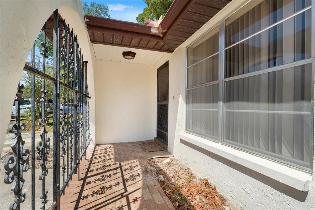 A covered brick entryway features a decorative black iron gate and a glass storm door — 8511 LONG BOAT LANE, HUDSON, FL