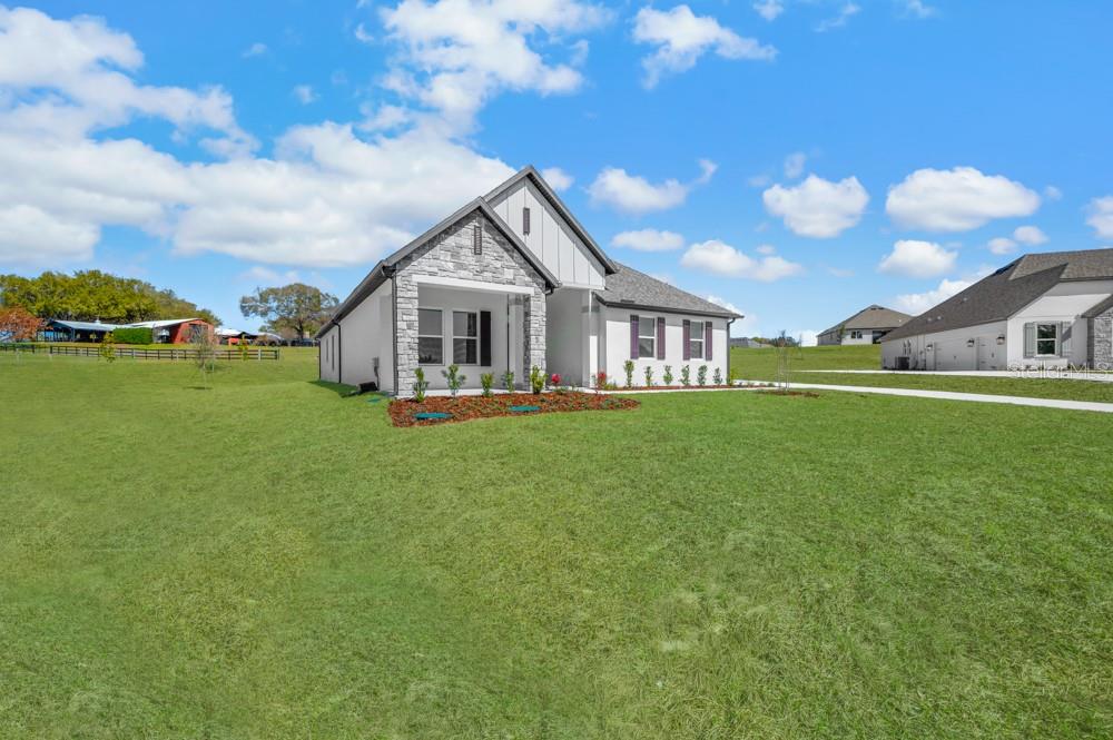 A single-story house with a stone facade and white siding sits on a grassy lot — 3845 SADDLE HILL TRAIL, FRUITLAND PARK, FL