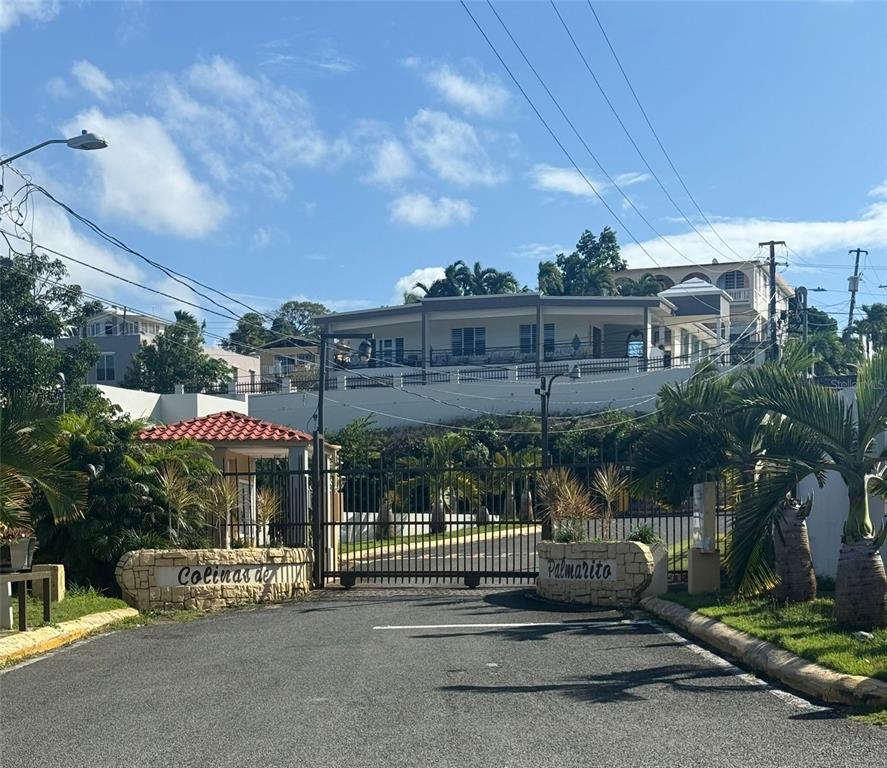A gated entrance with stone pillars leads to a multi-story house on a hill — COLINAS DE PALMARITO, ARECIBO, PR