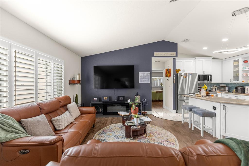 A living room with a brown leather sofa, dark blue accent wall, and open kitchen — 13834 SW 114TH AVENUE, DUNNELLON, FL