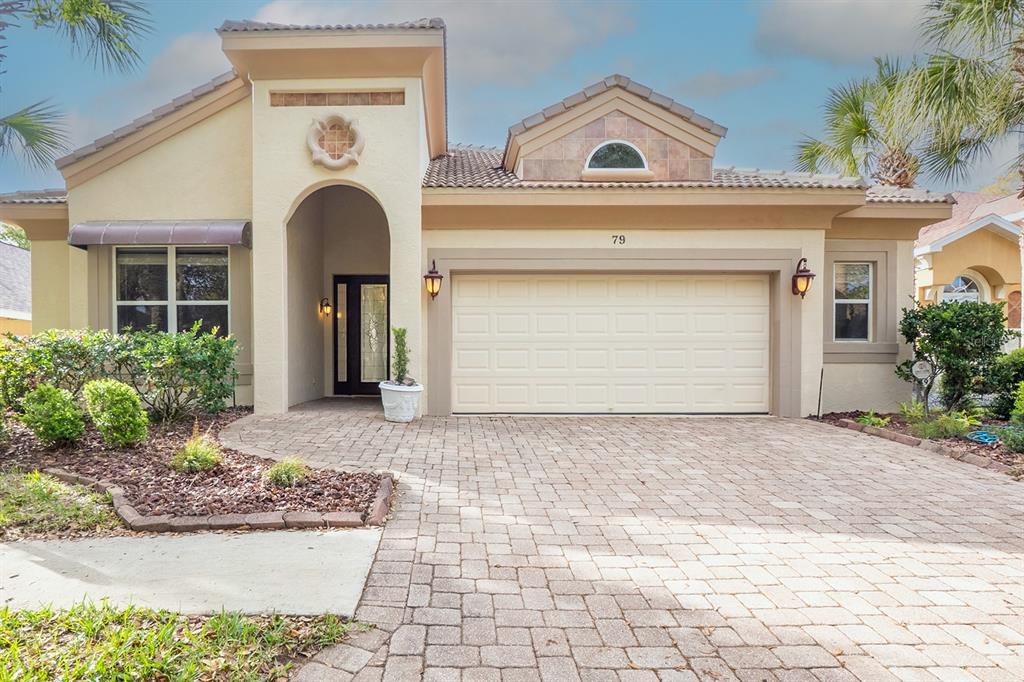 The exterior entryway features a paved walkway, a dark wood front door, and a palm tree — 79 SOUTHLAKE DRIVE, PALM COAST, FL