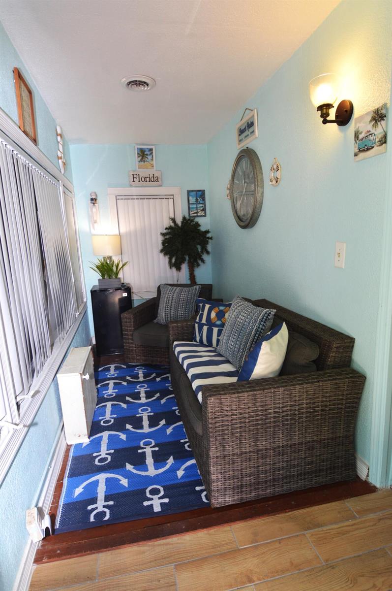 A sunroom features light blue walls, wicker furniture, and a blue anchor-patterned area rug — 711 Cedar Place, Fort Pierce FL 34950, FORT PIERCE, FL