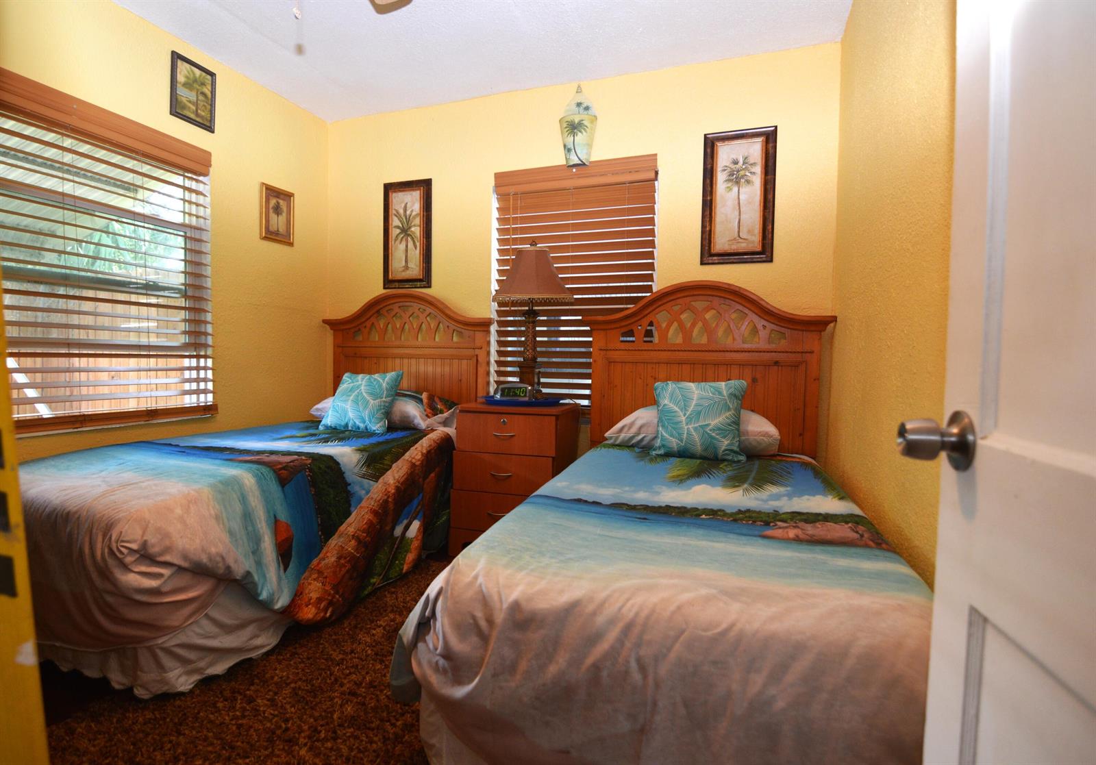A bedroom with two twin beds, yellow walls, wood headboards, and tropical-themed bedding — 711 Cedar Place, Fort Pierce FL 34950, FORT PIERCE, FL