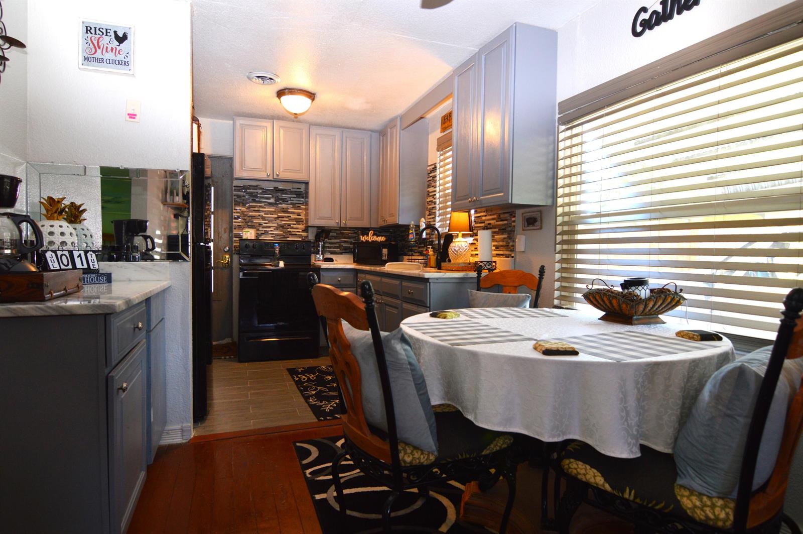 A kitchen features blue cabinets, a black stove, a dining table, and wood flooring — 711 Cedar Place, Fort Pierce FL 34950, FORT PIERCE, FL