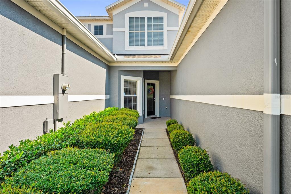 A concrete walkway leads to the front entrance of a two-story gray stucco house — 1562 TRAVERTINE TERRACE, SANFORD, FL