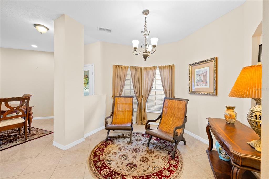 A dining area features a chandelier, two wooden chairs on a round rug, and tile flooring — 1562 TRAVERTINE TERRACE, SANFORD, FL