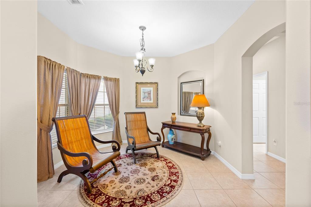 A sunlit sitting area features two wicker chairs, a round rug, and a wooden console table — 1562 TRAVERTINE TERRACE, SANFORD, FL