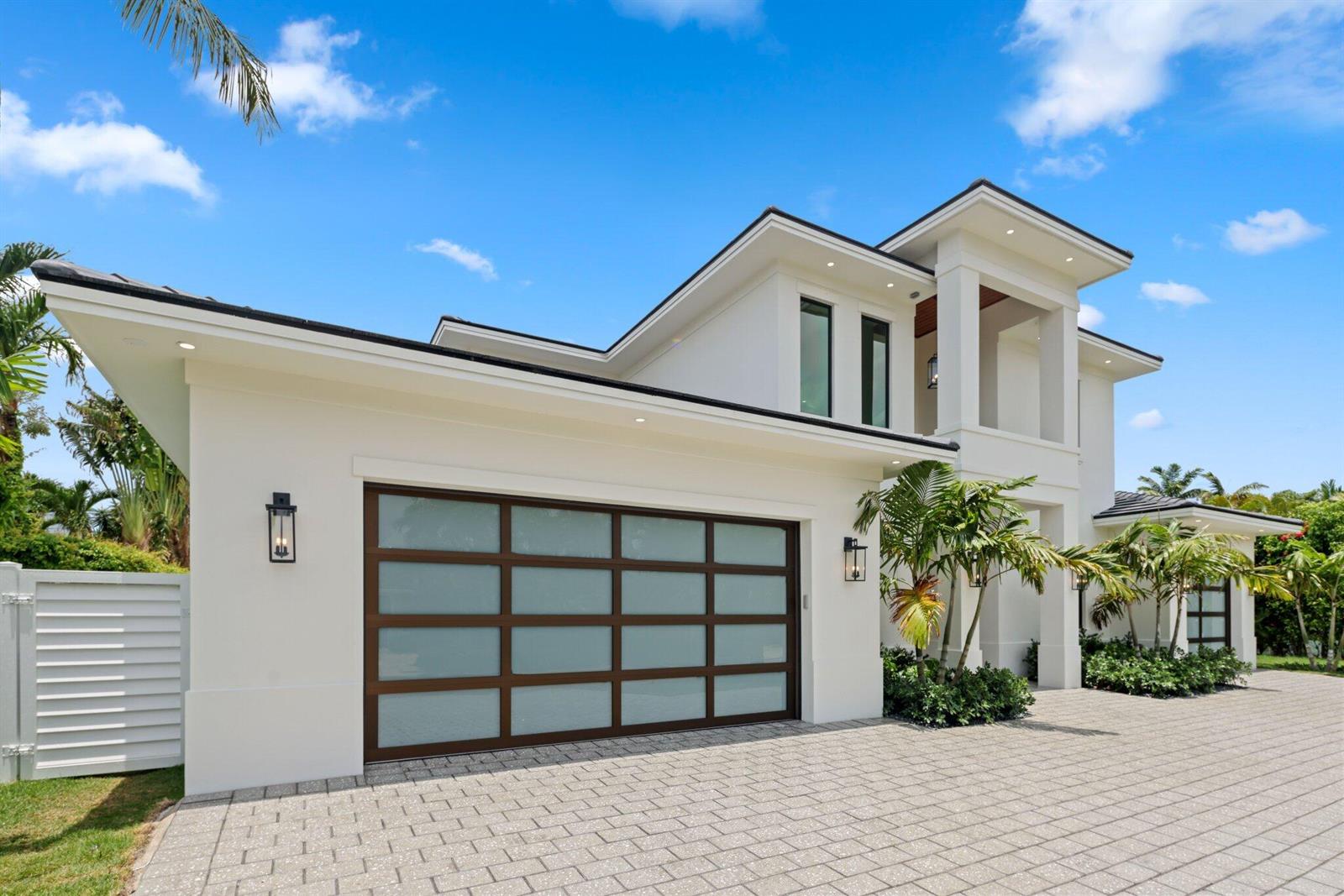 A modern white two-story house features a frosted glass garage door and a paved driveway — 1160 Emerald Drive, Riviera Beach FL 33404, RIVIERA BEACH, FL