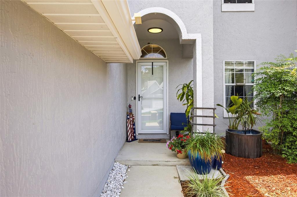 A concrete walkway leads to the white front door of a gray stucco home — 2409 SW 20TH TERRACE, OCALA, FL