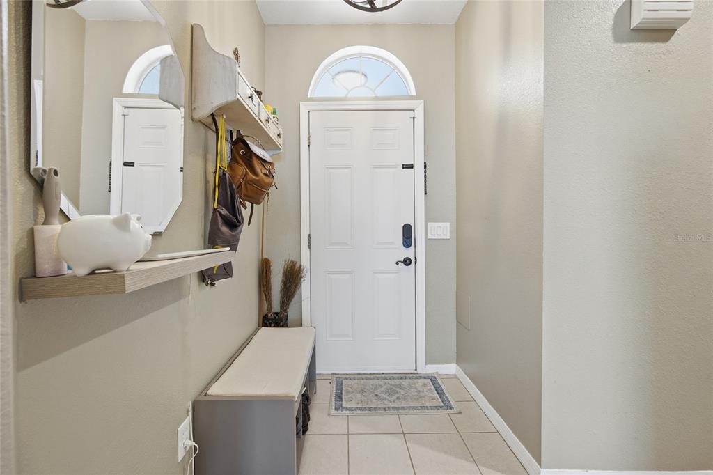 An entryway features a white front door, a storage bench, and wall-mounted shelving with hooks — 2409 SW 20TH TERRACE, OCALA, FL