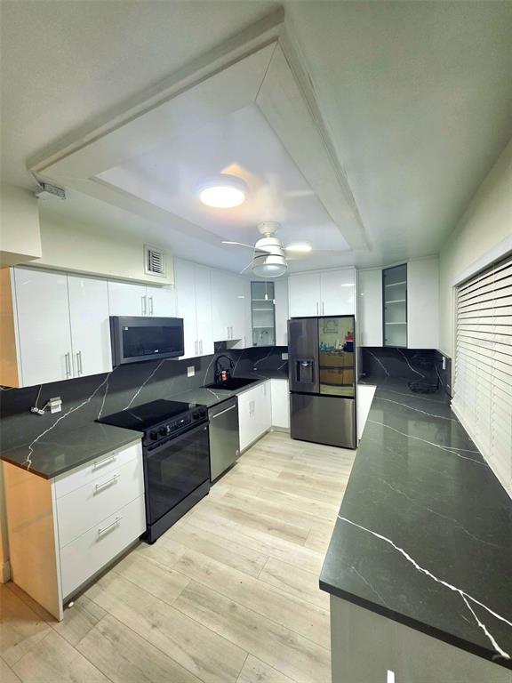A kitchen features white cabinets, dark countertops with white veining, and stainless steel appliances — 4020 W PALM AIRE UNIT 402, POMPANO BEACH, FL