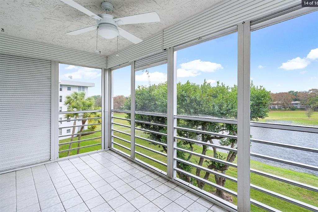 A screened-in balcony with white tile flooring, a ceiling fan, and views of a pond — 4020 W PALM AIRE UNIT 402, POMPANO BEACH, FL