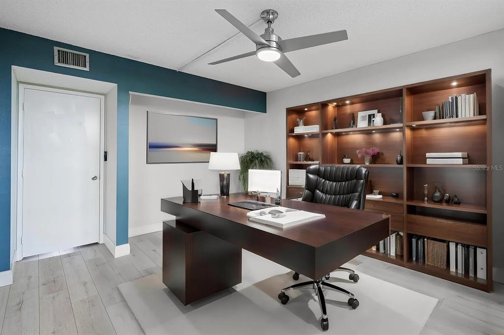 A home office features a dark wood desk, built-in shelving, and a ceiling fan — 4020 W PALM AIRE UNIT 402, POMPANO BEACH, FL