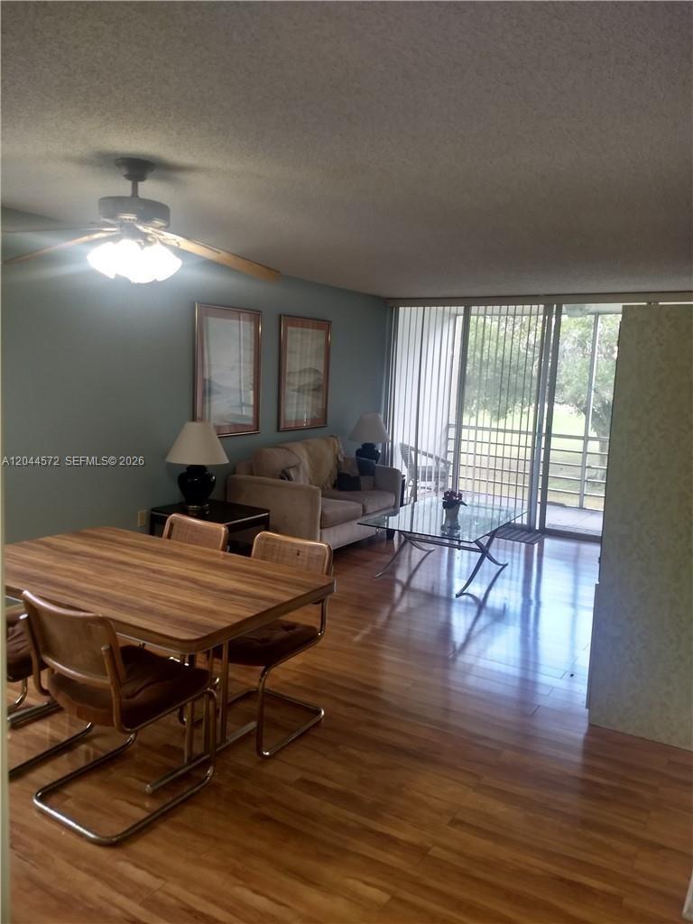 A dining area and living room feature wood-look flooring, a ceiling fan, and a balcony — 9410 Tangerine Pl # 204, Davie FL 33324, DAVIE, FL