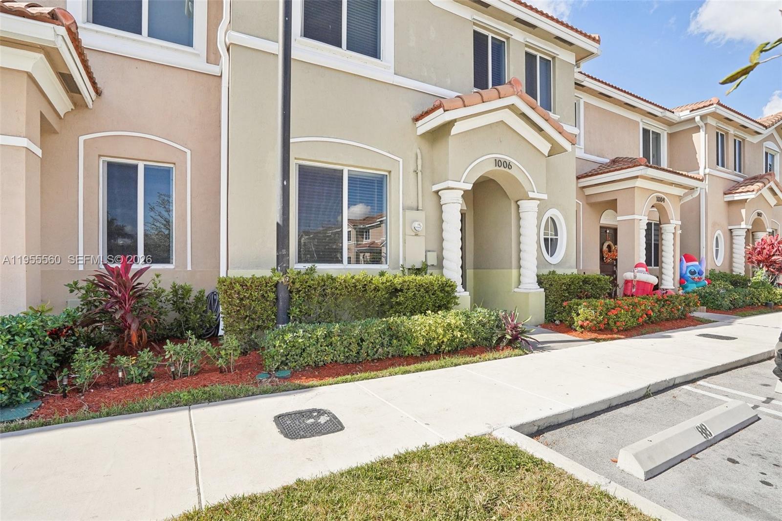 A multi-story townhouse exterior features a beige stucco facade, arched entryway, and landscaped front yard — 1006 SE 23rd Ave, Homestead FL 33035, HOMESTEAD, FL