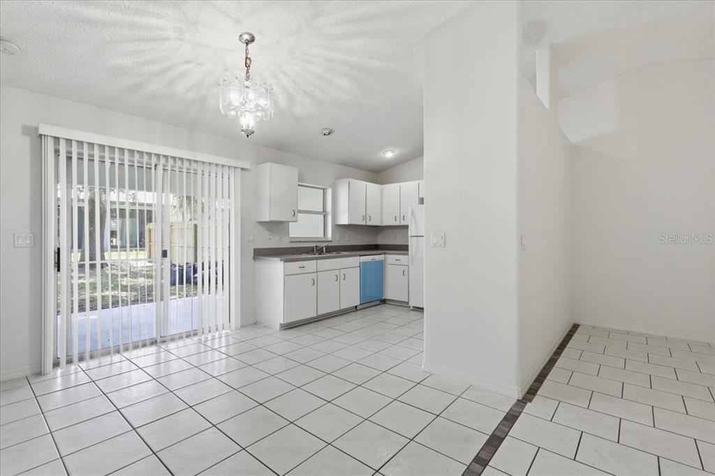 A kitchen and dining area with white cabinets, tiled floors, and a sliding glass door — 4 PONY LANE UNIT A & B, PALM COAST, FL