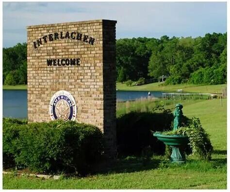 A brick welcome sign for Interlachen stands near a lake, green grass, and a birdbath — 175 Park Avenue, FL 32148, FL