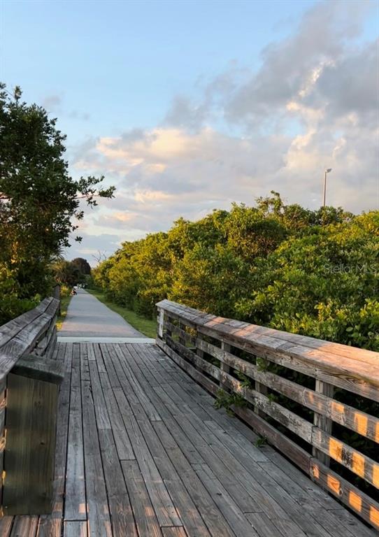 A wooden boardwalk leads to a paved path surrounded by lush green trees and shrubs — 168 ROTONDA BOULEVARD E, ROTONDA WEST, FL