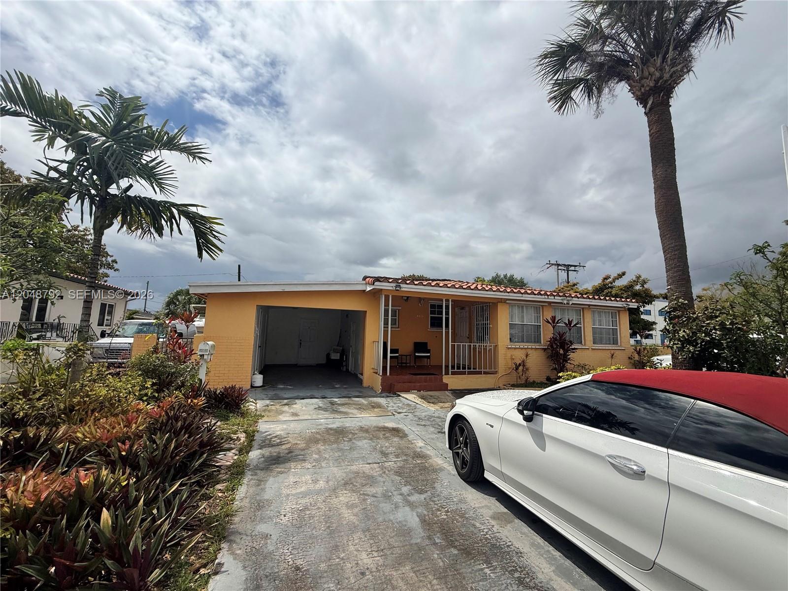 A yellow single-story house with a carport and a white convertible in the driveway — 4470 W 1st Ave, Hialeah FL 33012, HIALEAH, FL