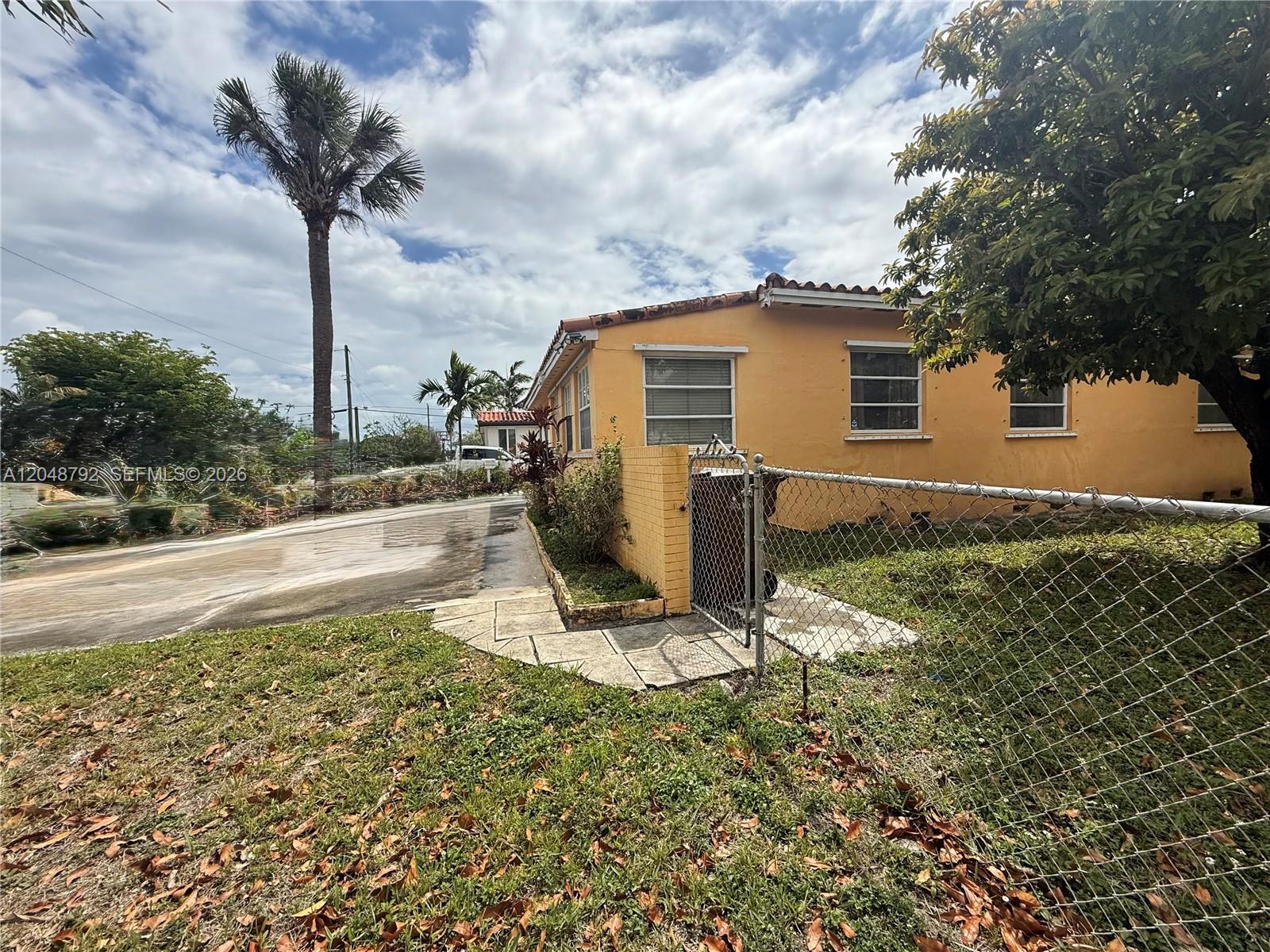 A yellow house with a tile roof sits behind a chain-link fence and palm trees — 4470 W 1st Ave, Hialeah FL 33012, HIALEAH, FL
