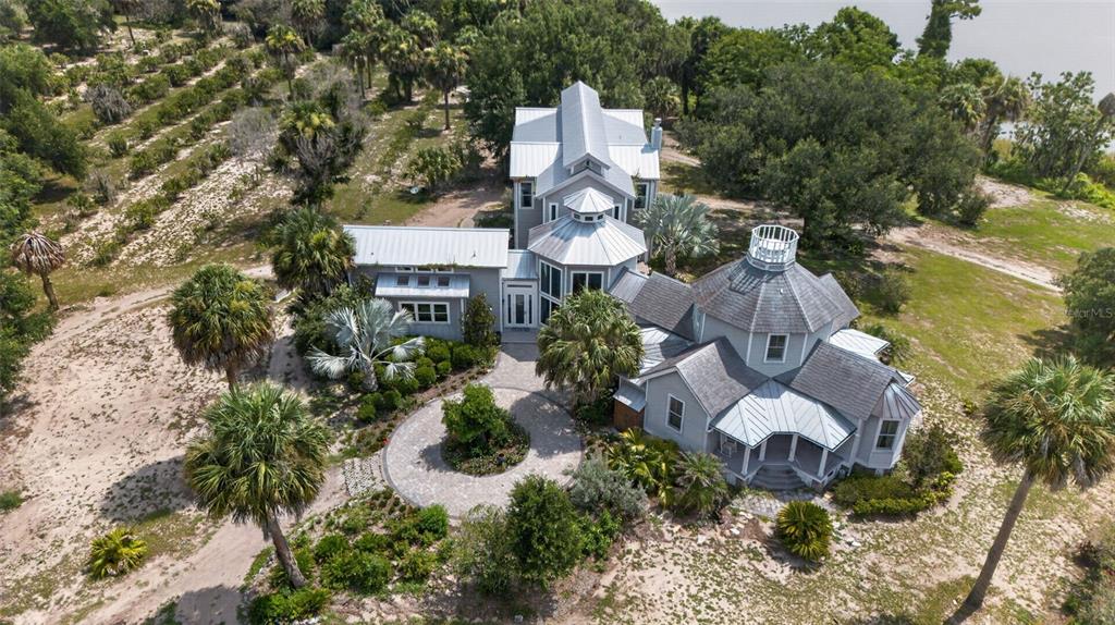 An aerial view shows a multi-section gray house with metal roofs and a circular driveway — 7950 BANNON FISH CAMP ROAD, HAINES CITY, FL