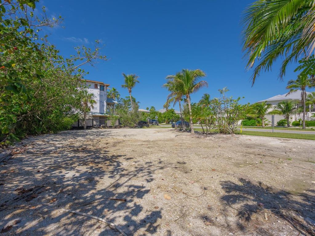 A vacant, sandy residential lot is surrounded by palm trees and nearby houses — 720 BROADWAY STREET, LONGBOAT KEY, FL