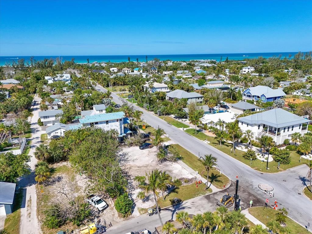 An aerial view shows a coastal neighborhood with houses, palm trees, and a vacant lot — 720 BROADWAY STREET, LONGBOAT KEY, FL