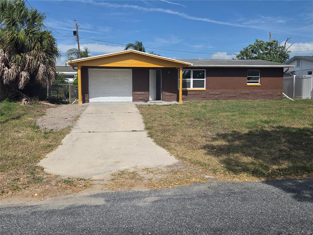 A house exterior features a brown brick facade, a covered carport, and yellow spiral columns — 4645 IRENE LOOP, NEW PORT RICHEY, FL