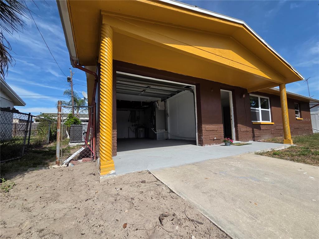 A brown exterior wall with a concrete porch, a yellow support column, and a doorway — 4645 IRENE LOOP, NEW PORT RICHEY, FL