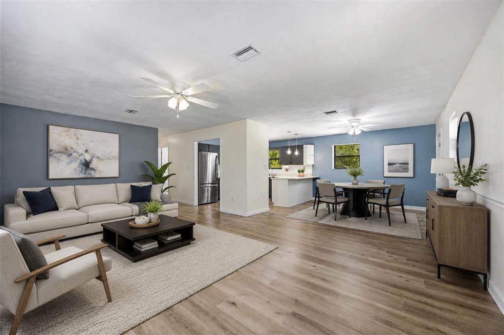 An open-concept living and dining area features blue accent walls, light wood flooring, and furniture — 9419 NW 235TH TERRACE, ALACHUA, FL