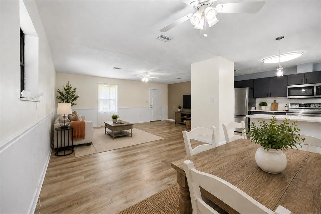 An open-concept living and dining area with light wood flooring and a modern kitchen — 9419 NW 235TH TERRACE, ALACHUA, FL