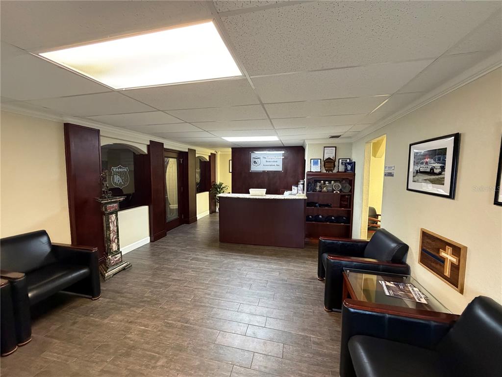 A reception area features dark wood furniture, black leather chairs, and wood-look tile flooring — 1302 W BUSCH BOULEVARD, TAMPA, FL