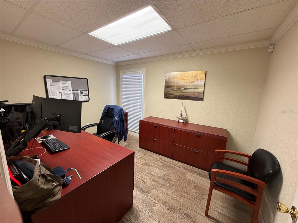An office features a red desk, a matching storage cabinet, and wood-look tile flooring — 1302 W BUSCH BOULEVARD, TAMPA, FL