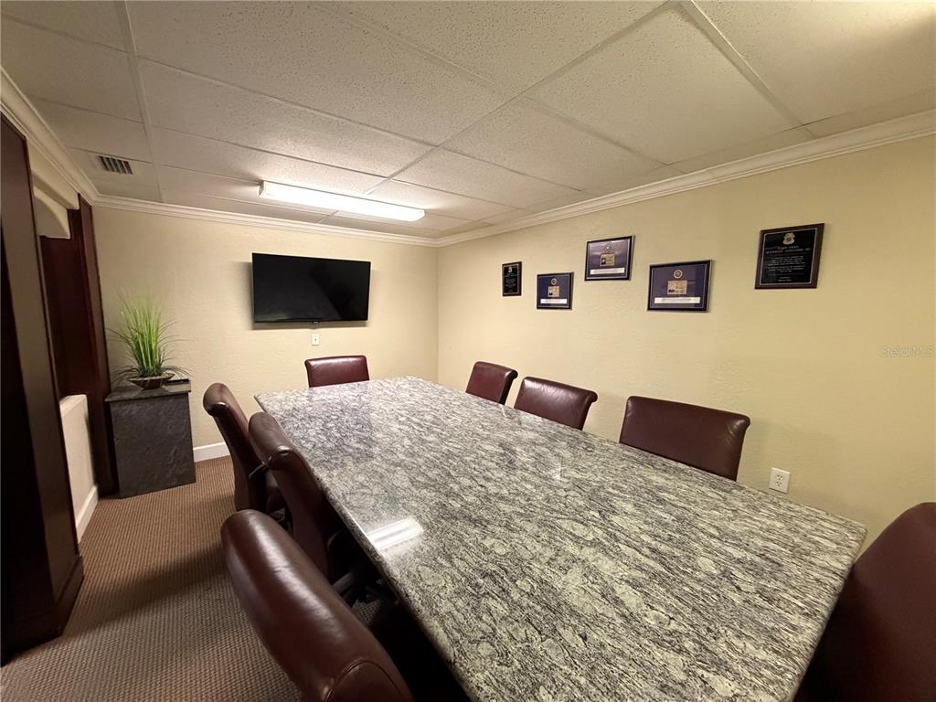 A conference room features a large granite table, leather chairs, and wall-mounted framed awards — 1302 W BUSCH BOULEVARD, TAMPA, FL