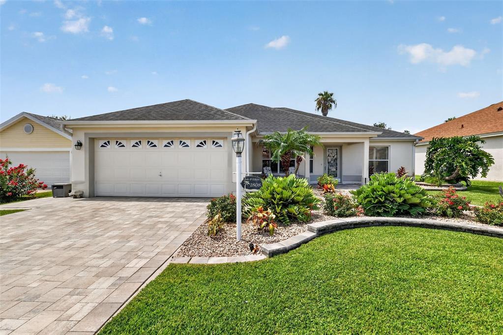 A single-story house with a paved driveway, a two-car garage, and landscaped front yard — 1808 SANTANA WAY, THE VILLAGES, FL